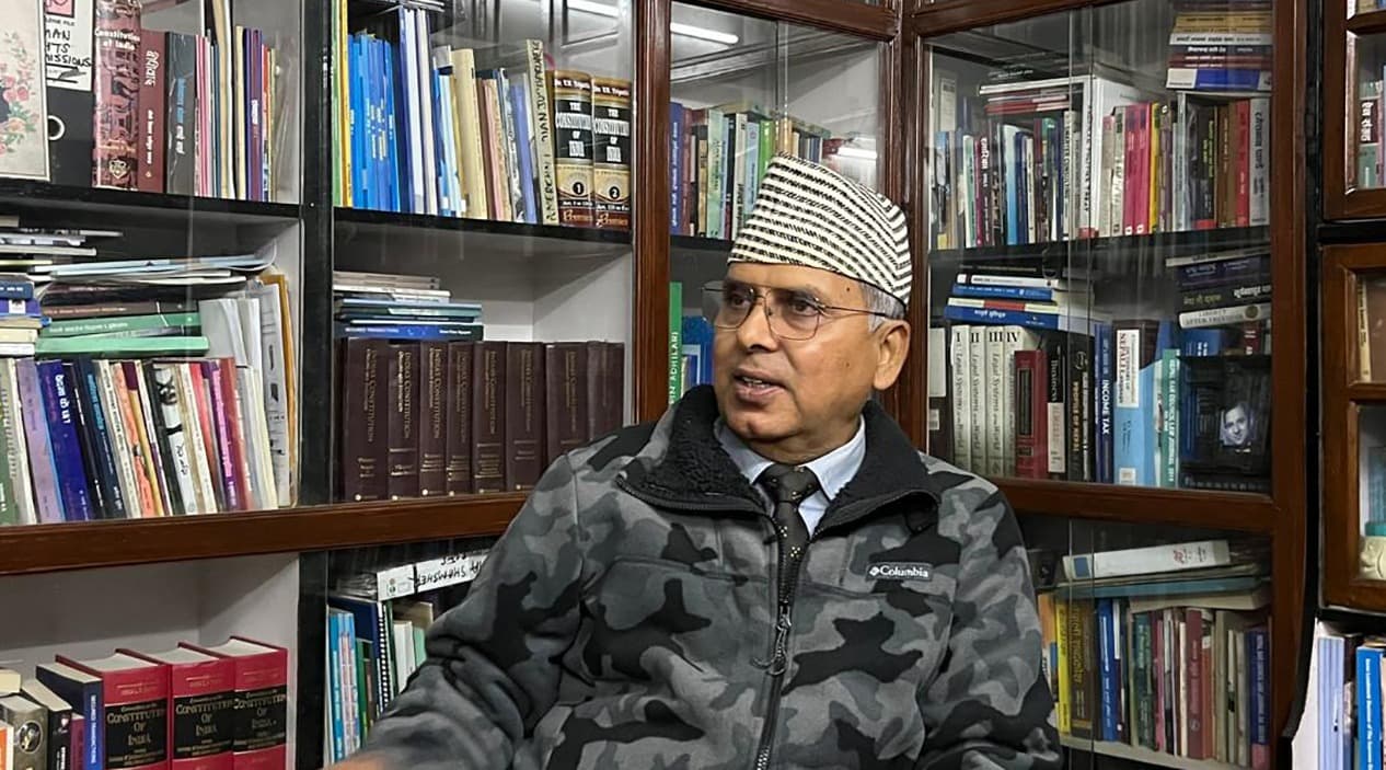 Dr Bipin Adhikari seated in front of his book collection